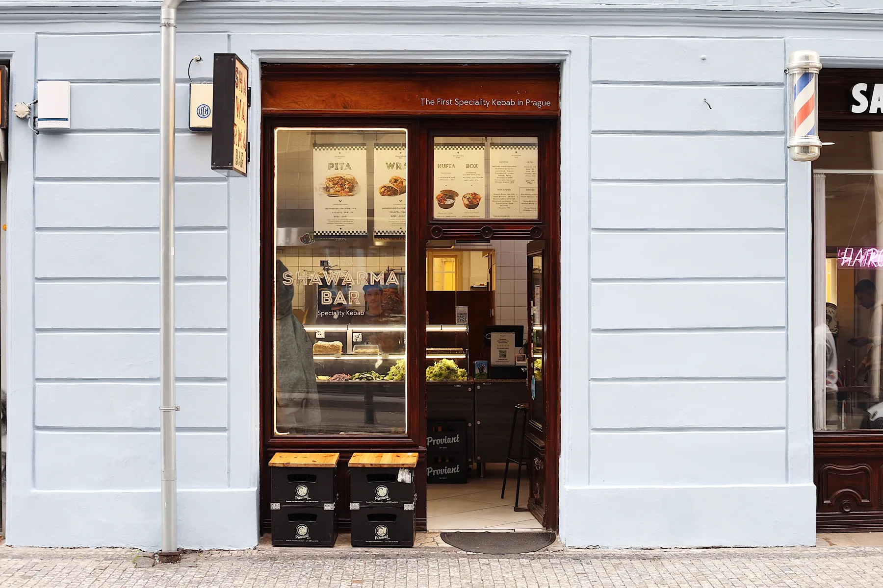 Vchod do MATOKA Shawarma Bar v Praze s dřevěnými dveřmi a menu ve výloze.