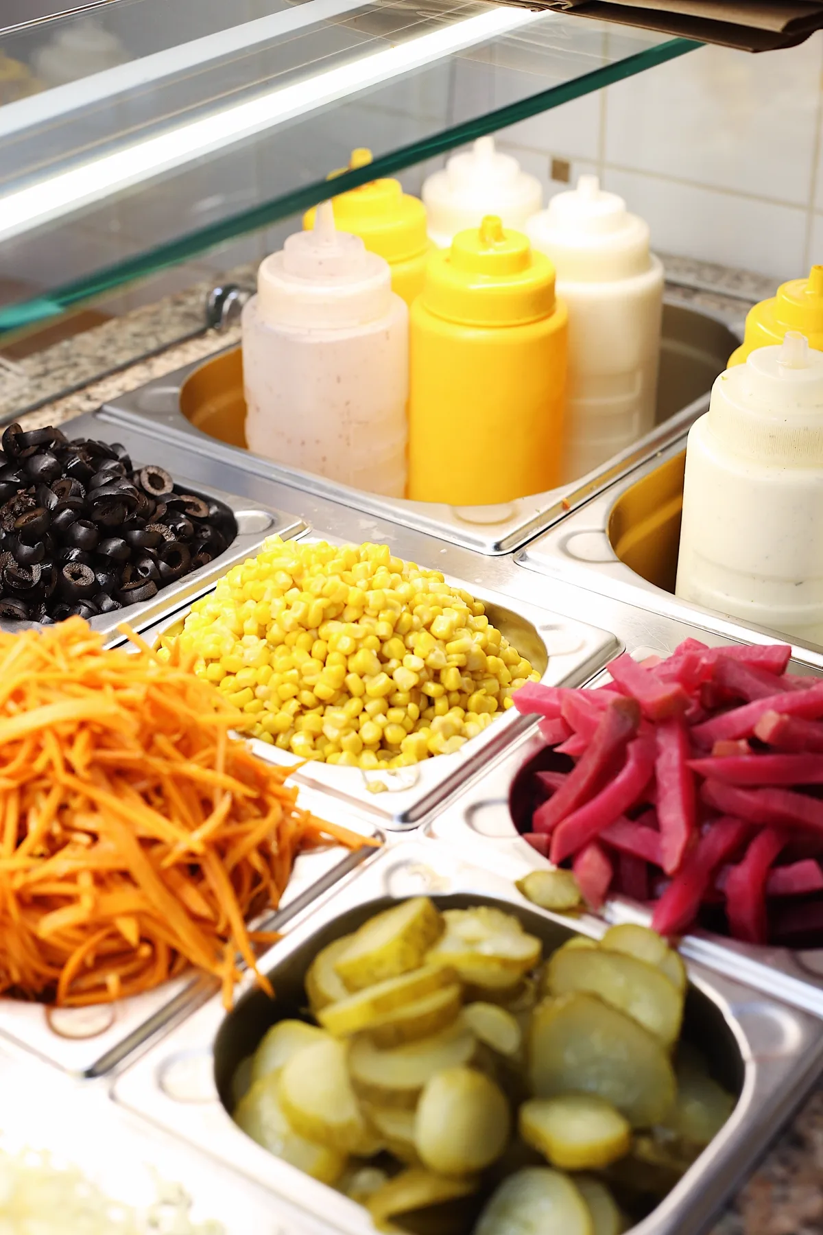 Čerstvé ingredience za pultem MATOKA Shawarma Bar: olivy, kukuřice, mrkev, nakládaná zelenina a domácí omáčky.
